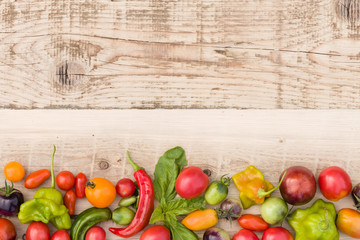 Closeup of multi-colored fresh organic vegetables: paprika, tomatoes, and herbs on natural wooden background. Healthy food concept