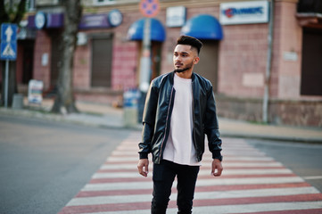 Stylish indian beard man at black leather jacket walking on zebra crossing. India model posed outdoor at streets of city.