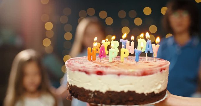 Children having birthday party, blowing out the candles on birthday cake. Group of kids celebraing birthday of their friend, cheering, having fun - happy childhood concept 4k