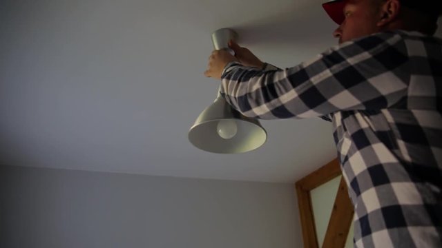 the electrician installs the ceiling lamp