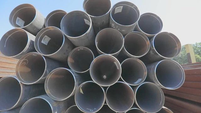 View through metal pipes of large diameter. Metal pipes of large diameter in a metal warehouse, large pipes in an open-air warehouse, large diameter pipes stacked in rows
