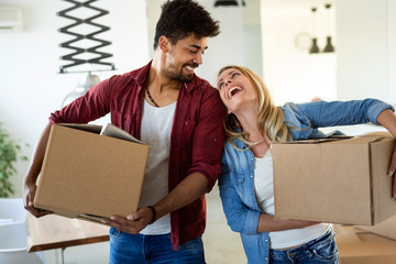 Young couple unpacking cardboard boxes at new home moving in concept