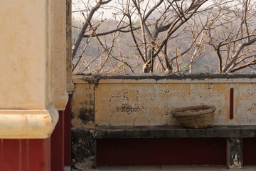 Abandonned basket on a stone bench at a buddhist temple monastery on a sunny afternoon in Sagaying Mandalay, Myanmar, Burma, Asia