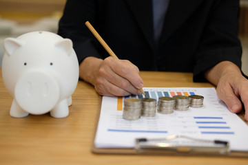 coin & piggy bank with woman writing on graph. money savings, cash deposit concept