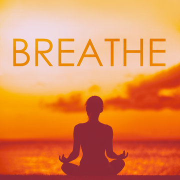 BREATHE yoga inspirational title on beautiful beach with woman meditating doing yoga at sunset. Word breathe written on copy space for inspiration and motivation in health and fitness concepts.