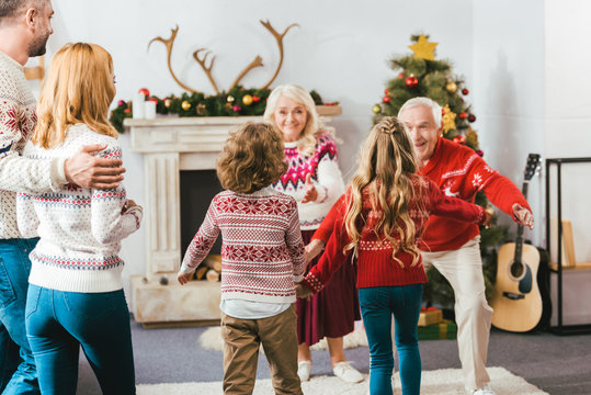 Rear View Of Kids Running To Hug Grandparents During Christmas Eve At Home