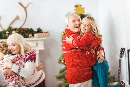 happy grandparents embracing with kids on christmas at home
