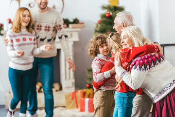 grandparents embracing with kids during christmas eve at home