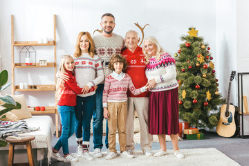 happy family embracing at home during christmas and looking at camera