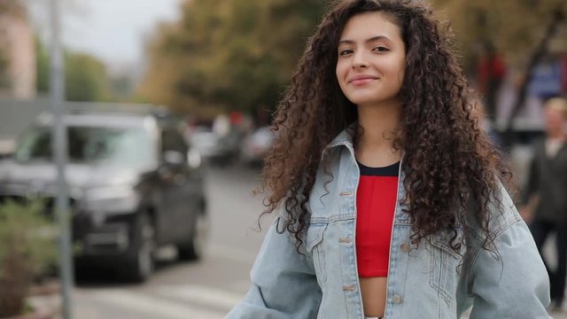 Portrait of young curly girl model posing in city