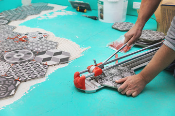 tiler cutting tile with cutter - obrazy, fototapety, plakaty
