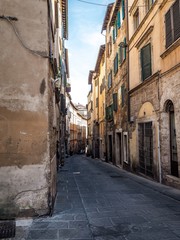 Charming old street of medieval towns of Italy - Perugia in Umbria, deserted, green shutters on windows, red flowers