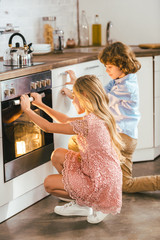 adorable kids looking at baking oven at kitchen
