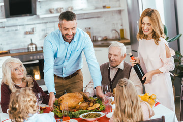 smiling family with turkey celebrating thanksgiving day at home