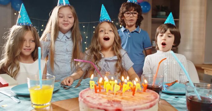 Children celebrating birthday party, blowing out the candles on birthday cake. Group of kids having fun on birthday party - happy childhood concept 4k