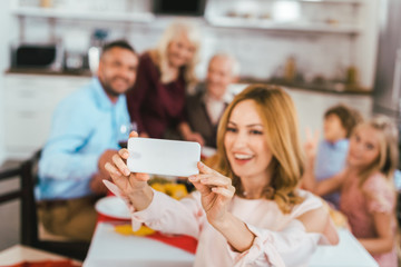happy young woman taking selfie with her family during thanksgiving dinner