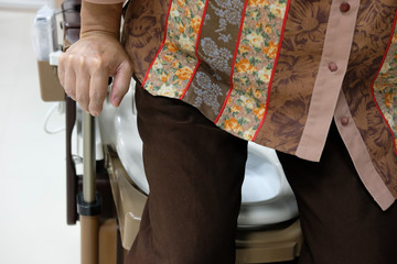 old woman use portable mobile plastic toilet near  patient bed