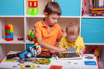 Fototapeta premium Two boys ?hild collects robot from the plastics details