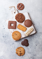 Fototapeta na wymiar Oat and chocolate cookies selection on wooden board on stone kitchen table background.