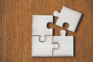 4 Four brown pieces of puzzle on wooden table, last piece of jigsaw puzzle to complete the mission, Business solutions, success and strategy concept