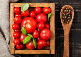 Organic Tomatoes with basil and pepper on spoon in vintage wooden box on wooden kitchen table