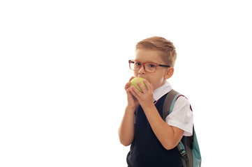 School boy wearing stylish glasses and formal uniform with green apple standing on white background