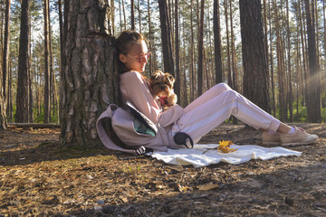 A woman with dog are relaxing in the forest. Girl with yorkshire terrier outdoor.