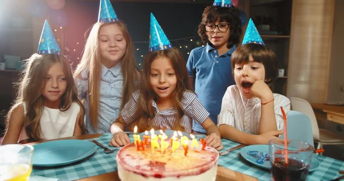 Children celebrating birthday party, blowing out the candles on birthday cake. Group of kids having fun on birthday party - happy childhood concept 4k