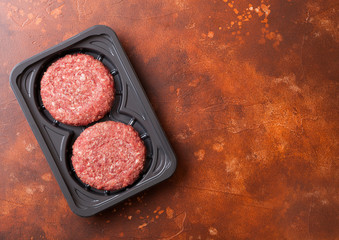 Plastic tray with raw minced home made grill beef burgers with spices and herbs. Top view.