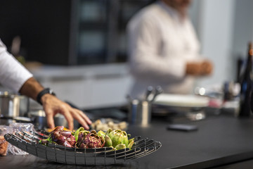 Artichokes in a basket in a modern kitchen. In the background a chef cooking