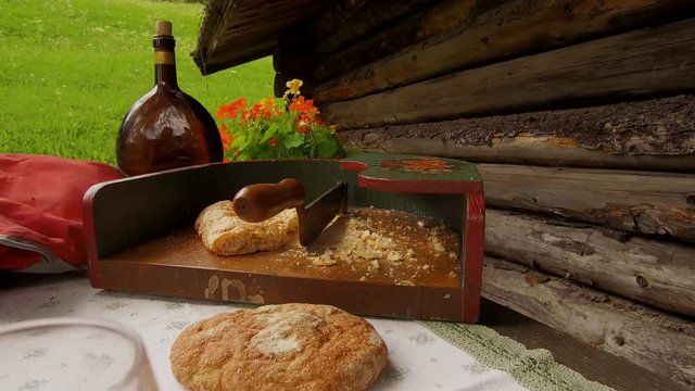 Close detail on a teenager dressed in typical Tyrolean dress, cut dry bread with a typical Tyrolean bread cut
