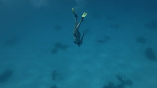 A woman in a mask and fins dives to the depths (Underwater shot, 4K / 60fps)
