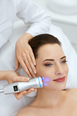 Beauty. Woman Doing Blue Light Facial Treatment On Face Skin