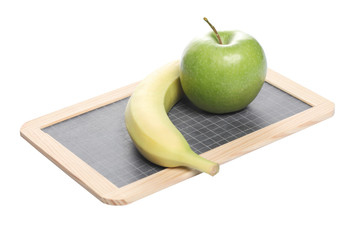 school concept: a greeen apple and a banana on a chalk board isolated on white background