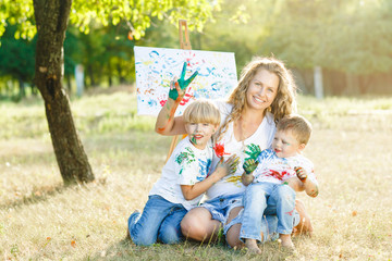Happy family drawing outdoors. Young mother having fun with her little children