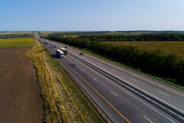 Cars drive on the highway outside the city on a cloudless day.