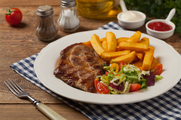Grilled pork neck served with French fries and salad.