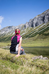 Naklejka premium Junge blonde Frau rastet am Ufer eines Bergsees, Österreich