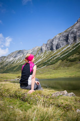 Junge blonde Frau rastet am Ufer eines Bergsees, Österreich