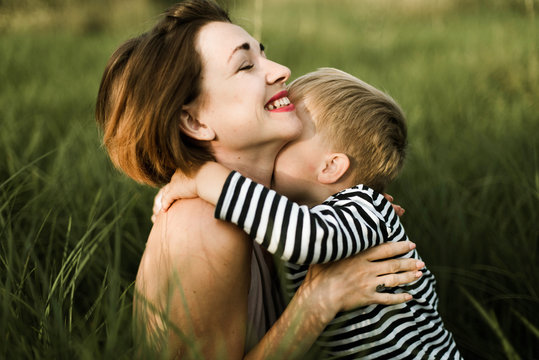 portrait of mother and son sitting in green grass