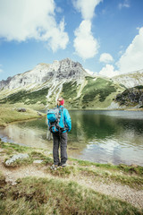 Junge blonde Frau betrachtet die Landschaft in den Berge, Bergsee und Gipfel