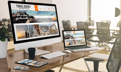 computer, laptop, tablet, and phone with responsive travel website  at office mockup