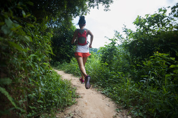 Young woman trail runner running on tropical forest trail