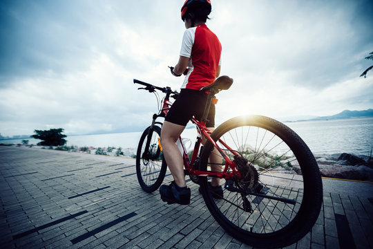 Woman cyclist use mobile phone while riding Mountain Bike on seaside
