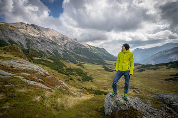 Fototapeta premium Junger selbstbwusster Mann in den Bergen, stehend, Blick in die Ferne, Abenteuer