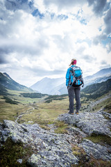 Junge blonde Frau in den Bergen, stehend, Blick in die Ferne, Abenteuer