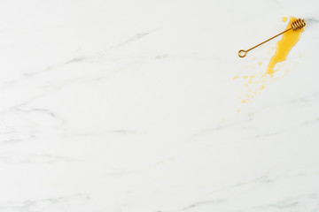 Honey concept. Top view of golden dipper with honey on white marble background. Horizontal flat lay with copy space.
