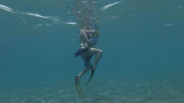 Woman and little boy in mask, snorkel and fins swim on the surface of water (underwater view, 4K / 60fps)
