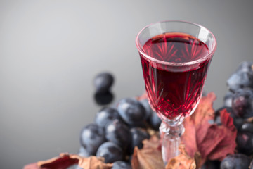Crystal glass of red wine and grapes .