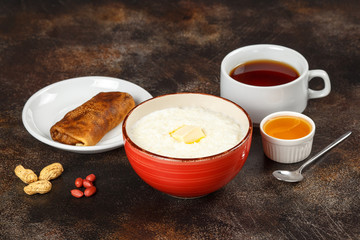 Oatmeal porridge in bowl, stuffed crepe and tea